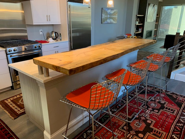 Modern retro kitchen with raised live edge slab bar top and fabulous red stools.