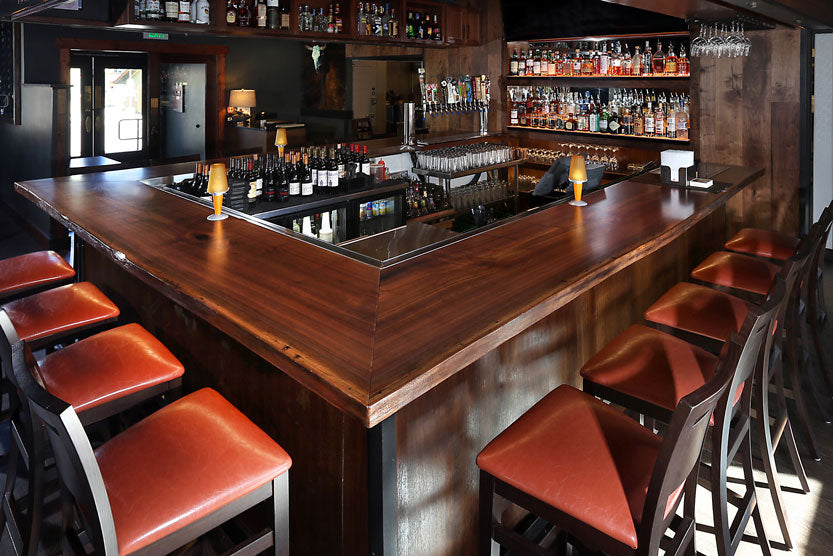 Elegant and welcoming Black Walnut bar top at Tavern West custom made to fit the space.