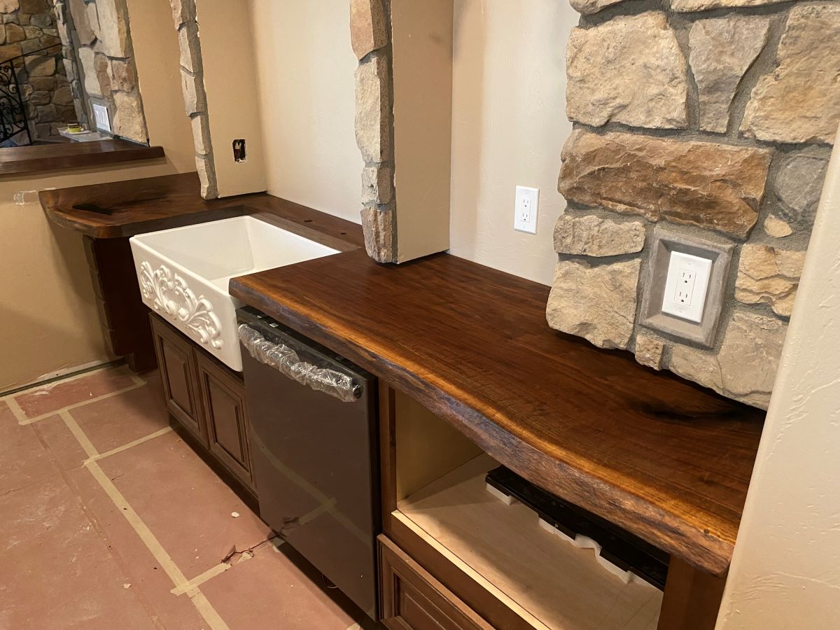 Custom made solid wood live edge bar top with sink cutout and wall details.