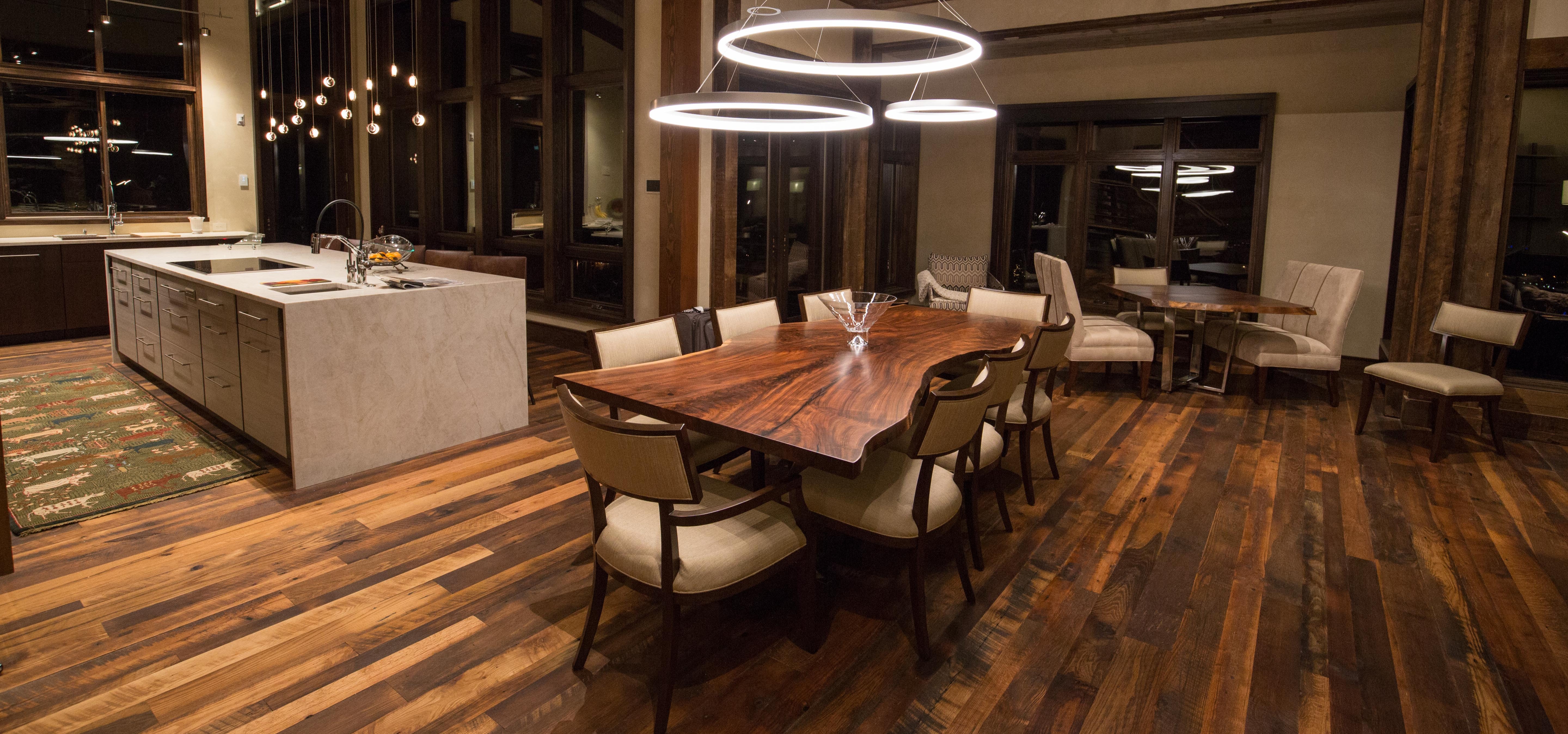 Single slab live edge walnut dining table in designer living room kitchen area with gorgeous lighting.