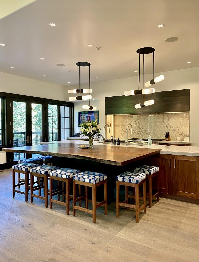 Huge solid walnut kitchen island seating area with custom stools and luxury designer lighting.