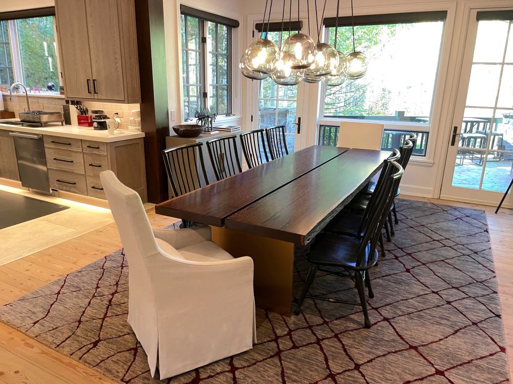 Wenge live edge slab dining table with reveal down the center and gold pillar legs in a beautiful dining room.