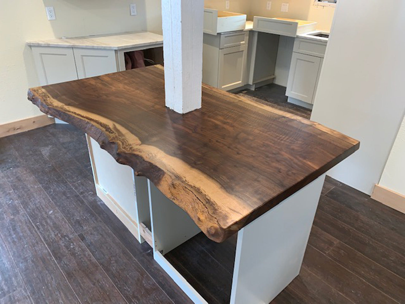 Walnut slab kitchen island with structural beam cutout.