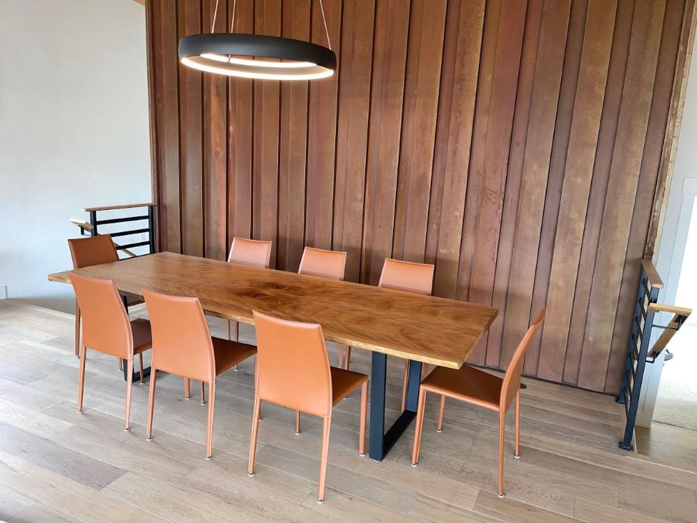Cherry bookmatch slab dining table in mid century modern wood paneled room with ultra cool leather chairs. 