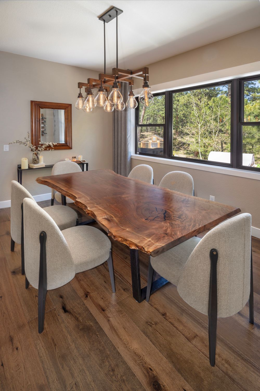 Claro walnut single slab live edge modern dining table with white chairs and modern farmhouse lighting.