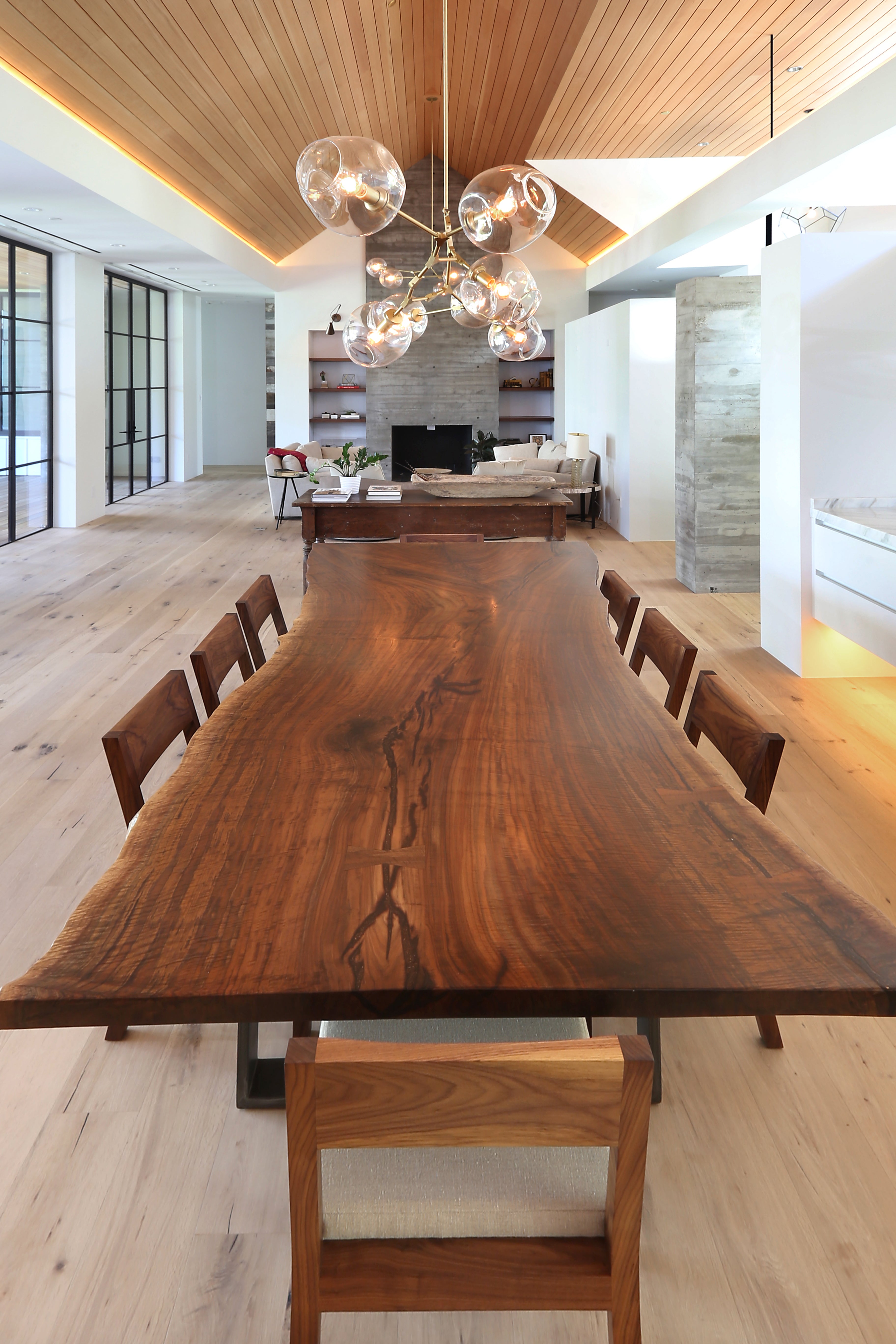 Claro Walnut single slab live edge dining table with designer lighting in modern white interior. 